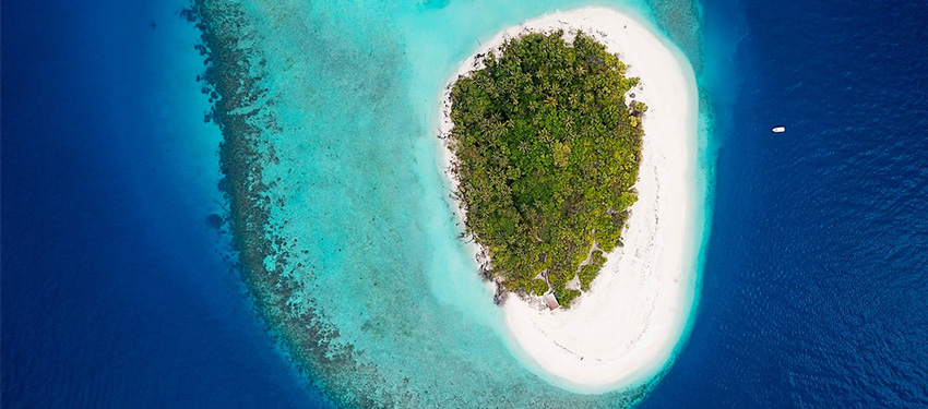 Aerial View of island surrounded by clear blue ocean.