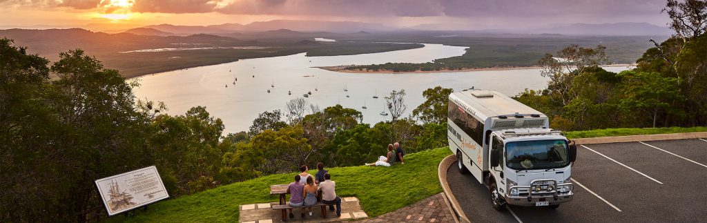 Sunset view across the Endeavor River in Cooktown with tour bus in foreground 