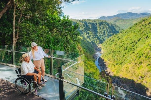 man and woman in wheelchair on a wooden viewing platform overlooking a waterfall and smiling